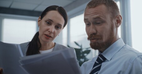 Marketing professionals or financial traders study papers and documents, discuss project ideas, brainstorm strategy. Two employees working in modern office of international company. Business concept.