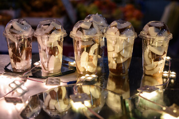 Large plastic cups filled with a freshly-cut coconut for blending into shakes and smoothies.