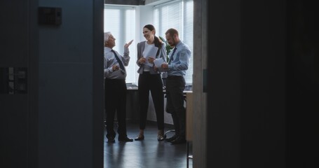 Excited senior boss walks into office room to colleagues. Happy team leader and company employees...