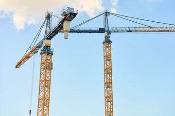 Construction crane against clear blue sky. Construction of new housing and development of urban infrastructure