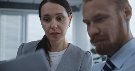 Portrait of two diverse financial specialists or marketing professionals working in modern office. Corporate business partners study documents, discuss strategy of company, brainstorm project ideas.