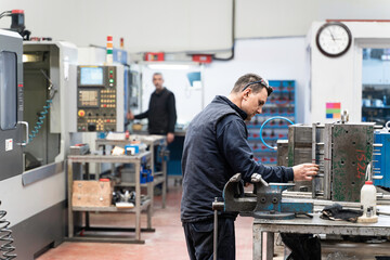 Lathe worker man working with a vernier and milling machine in a factory, using a caliper to check measurement.