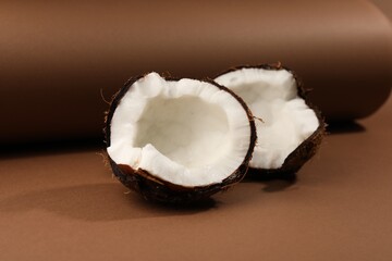 Halves of cracked coconut on brown background