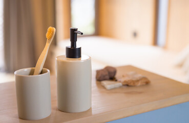 Bamboo toothbrush and soap dispenser on wooden bathroom counter, natural decor, at home