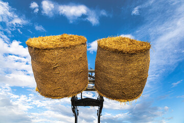Bales of hay, straw, lifted high by an agricultural telescopic turner. Bottom photo of hay bales. Beautiful sky for background. © Vesela