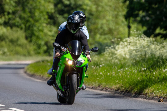 Man and pillion passenger riding on a Kawasaki Ninja motorcycle