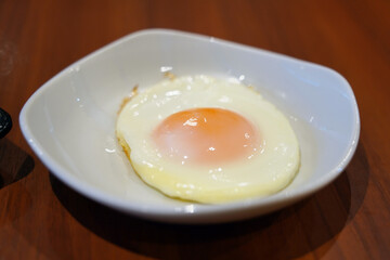 Fried egg in white bowl on wooden table