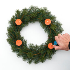 Künstlicher Adventskranz mit orangenen Kerzen, werden angezündet