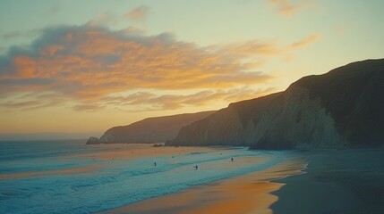 Obraz premium A breathtaking sunset over a sandy beach with cliffs in the background.