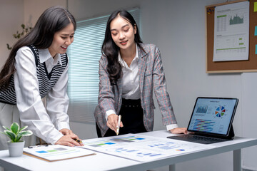 Two businesswomen analyzing financial charts on a desk