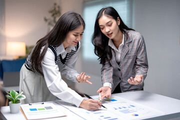 Two businesswomen working together discussing financial charts and data