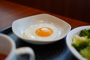 Fried egg in white bowl on wooden table