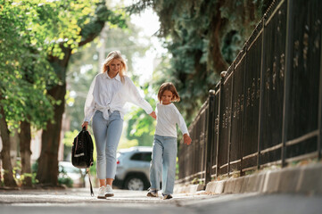 Obraz premium Leading the daughter to school. Little girl with her mother are outdoors together