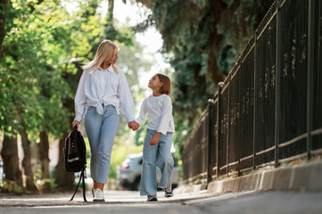 Leading the daughter to school. Little girl with her mother are outdoors together