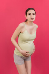 a pregnant girl who has a stomach ache stands on a colored background. isolated