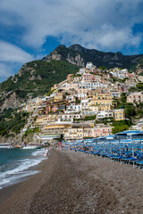 Vibrant Positano beach under the dramatic cliffs of Italy's Amalfi Coast in sunny weather