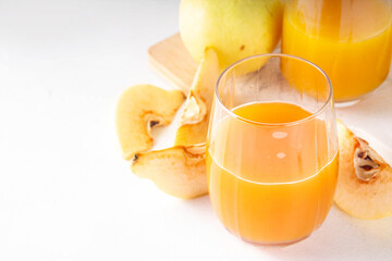 Fresh homemade apple quince juice in portioned glasses, with whole and sliced quinces c in the...