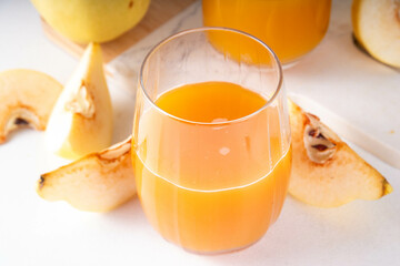 Fresh homemade apple quince juice in portioned glasses, with whole and sliced quinces c in the background