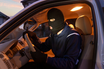 Thief stealing car at night wearing balaclava