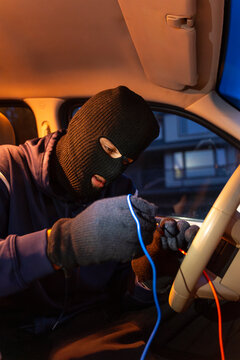 Masked thief hotwiring car ignition system