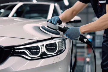 Car mechanic polishing headlight of vehicle during detailing work in auto service