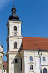 A baroque-style church tower in Sibiu, Romania, featuring an onion-shaped dome, a clock face, and arched windows.