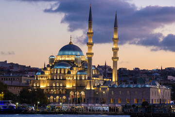 Naklejka premium Yeni Cami Mosque in Istanbul, Turkey, illuminated by lights at dusk