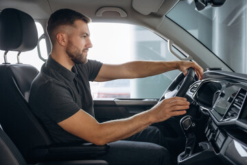 View from the side. Man is sitting in the car, driver