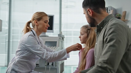 Smiling doctor measuring temperature in examination room. Father visiting clinic