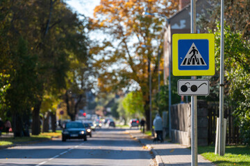 Pedestrian crossing sign on a sunny autumn day in a suburban neighborhood
