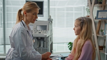 Fototapeta premium Pediatrician advising girl patient on health care closeup. Medical appointment