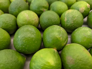 A close-up of vibrant green key limes, clustered together in a fresh, zesty display.