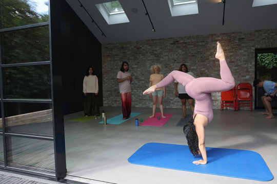 Instructor presenting handstand with splits to students during yoga class
