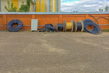 The drums of the coil with high-voltage wires stand on the butts next to coils of black plastic...