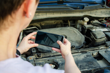 woman photographs breakdown in the open hood of a car