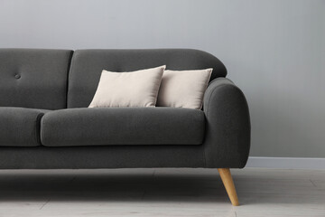Comfortable sofa with cushions near grey wall in room