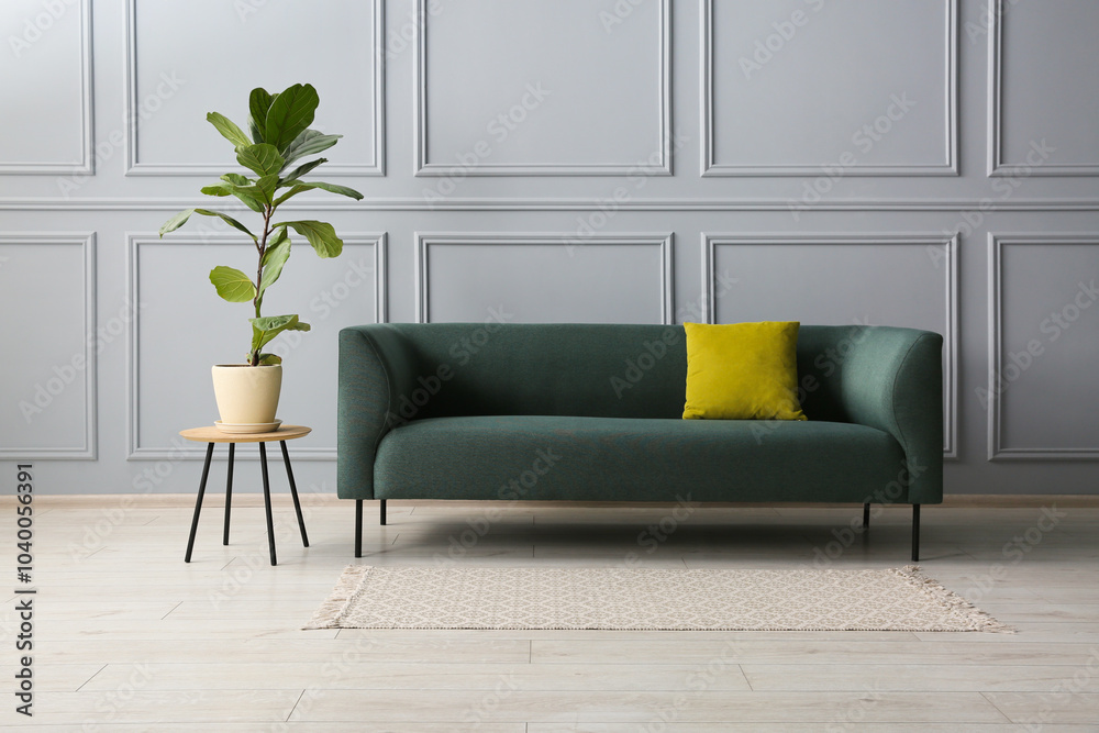 Sticker Stylish sofa with cushion and green plant near on side table grey wall