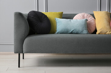 Stylish sofa with cushions near grey wall