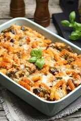 Delicious al forno pasta in baking dish on wooden table, closeup