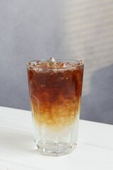 Refreshing espresso tonic drink on white wooden table