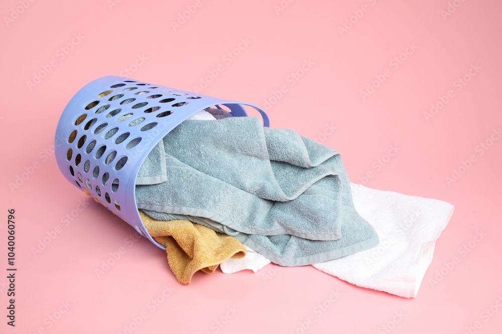 Wall mural Overturned laundry basket full of towels on pink background