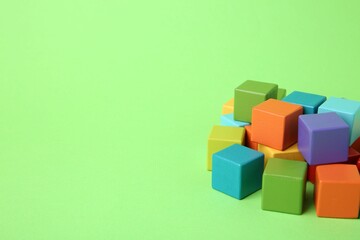 Many wooden colorful cubes on green background, space for text