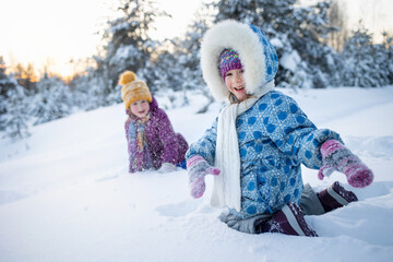 family, happy children playing snowballs at resort in winter against background of forest outdoor. Games and activities for Christmas holidays