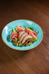 A gourmet salad featuring tomatoes and wine-marinated pear, elegantly presented on a blue plate. Ideal for themes of fine dining, healthy eating, and culinary artistry