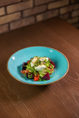 A delicious salad with mozzarella, beetroot, tomato, and fresh salad leaves, beautifully presented on a blue restaurant plate. Perfect for themes of healthy eating, gourmet dining, and fresh, vibrant 