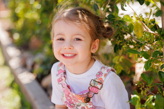 Preschool child sitting on edge of garden bed in bright sunny kindergarten yard