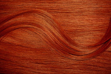 Red hair close-up as a background. Women's long orange hair. Beautifully styled wavy shiny curls....