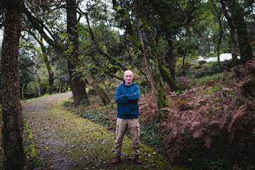 Obraz premium A man stands with his eyes closed on a park path, surrounded by the golden hues of autumn leaves, enjoying a quiet moment of peace and reflection.