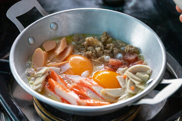 Eggs are cooked in a little pan served in, and topped with sweet sausage and pork stick. Pan Eggs or Kai Grata is a breakfast that is popular in Thailand.
