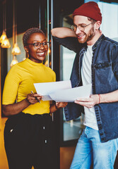 Cheerful african american businesswoman satisfied with  job of her male employee checking his...